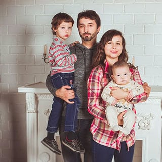 A family of four posing in front of a white brick wall.