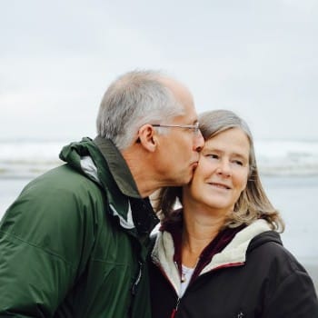 Man kissing woman on the cheek at the beach.