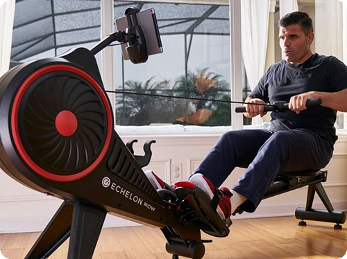 Man using a rowing machine indoors with a screen attached.