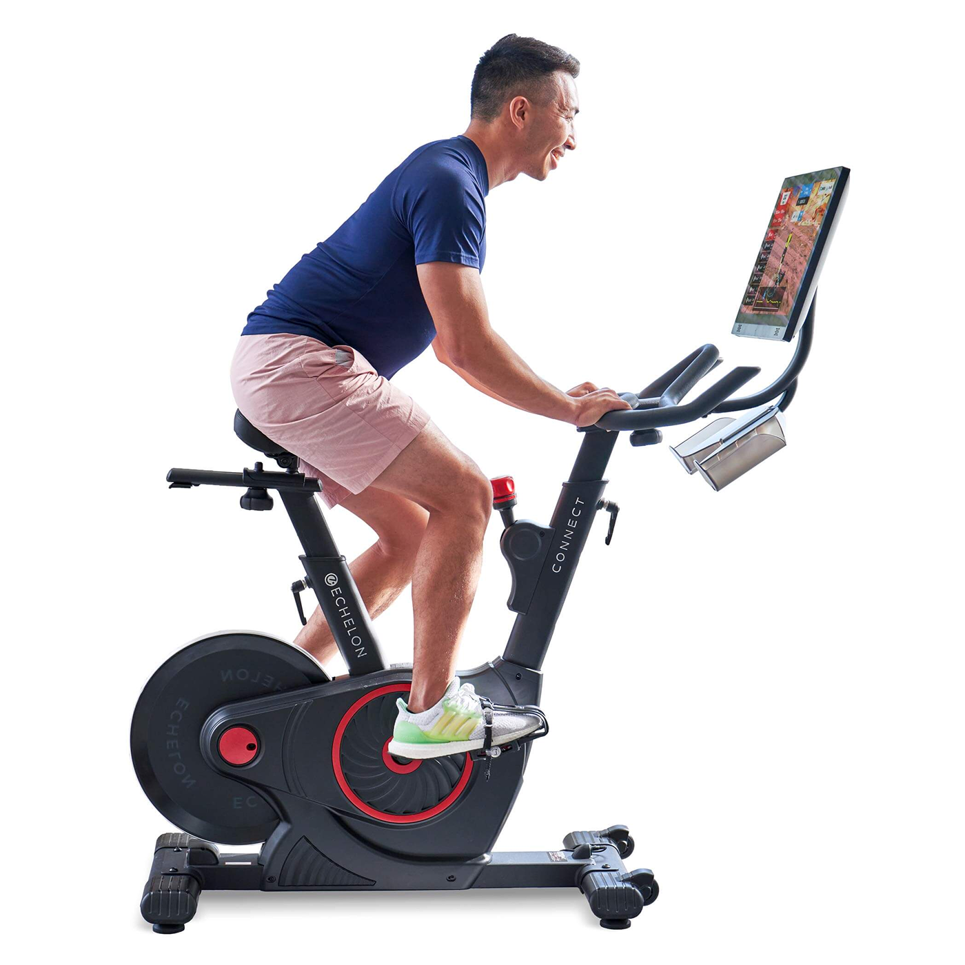 Man exercising on a stationary bike with a screen, wearing a blue shirt and pink shorts.