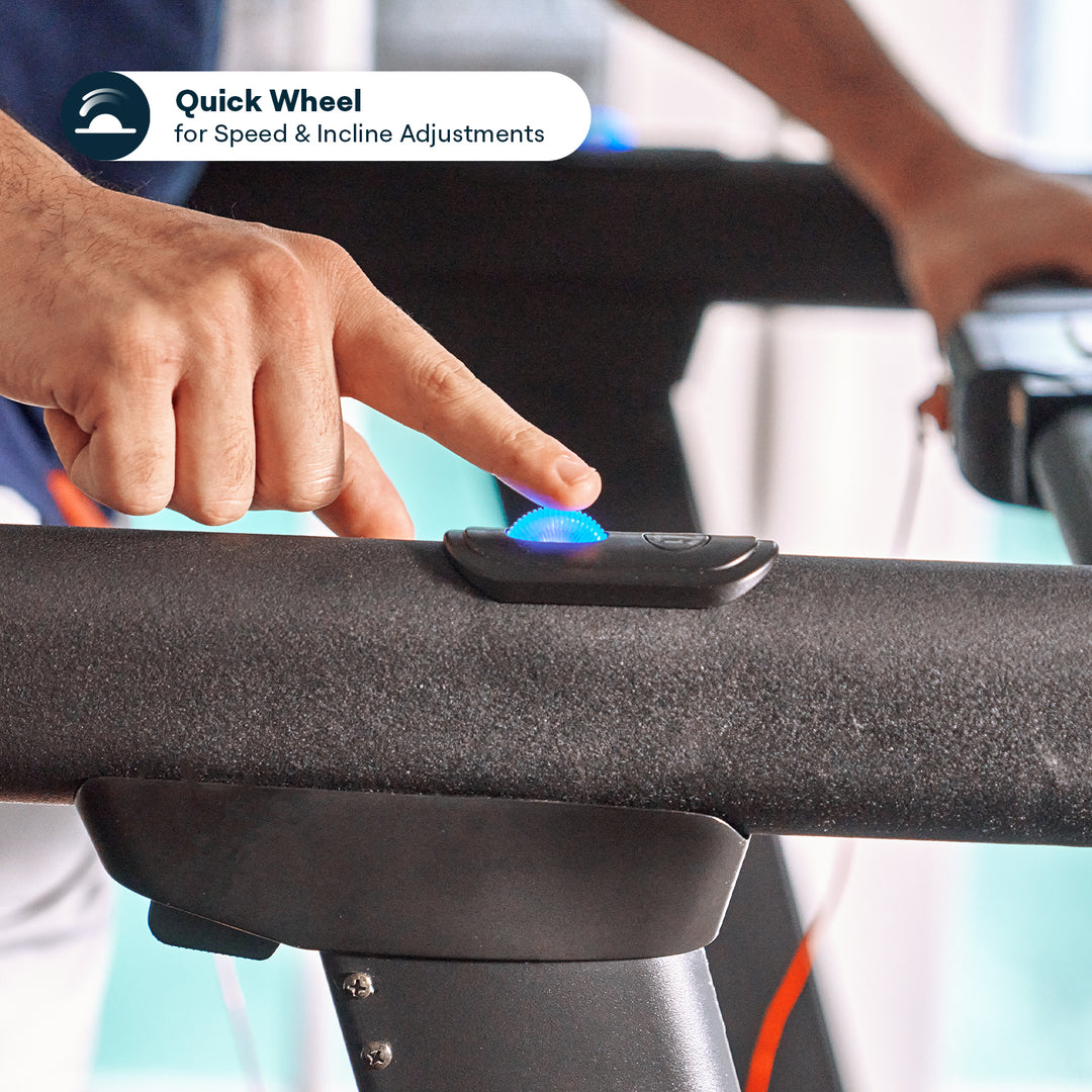 Person adjusting treadmill speed with a blue-lit control wheel.