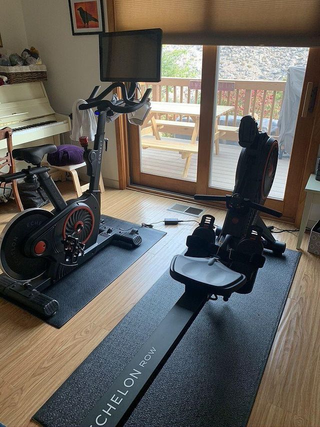 Home gym with exercise bike and rowing machine, large window, and a piano.