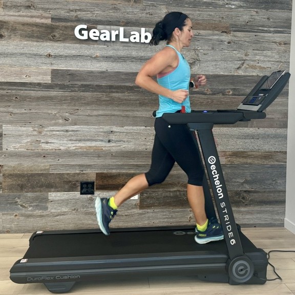 Person running on an Echelon treadmill in a room with wooden walls.