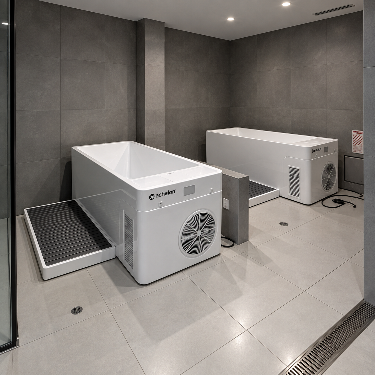 Two white Echelon cold plunge tubs sit in a modern room with gray tiled walls and floors.
