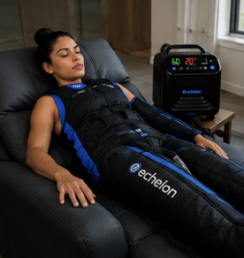 A woman relaxes in a chair wearing an Echelon full-body compression suit connected to a machine.