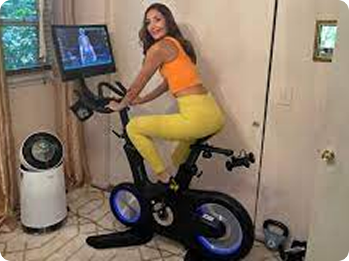 Person exercising on a stationary bike with a screen display.