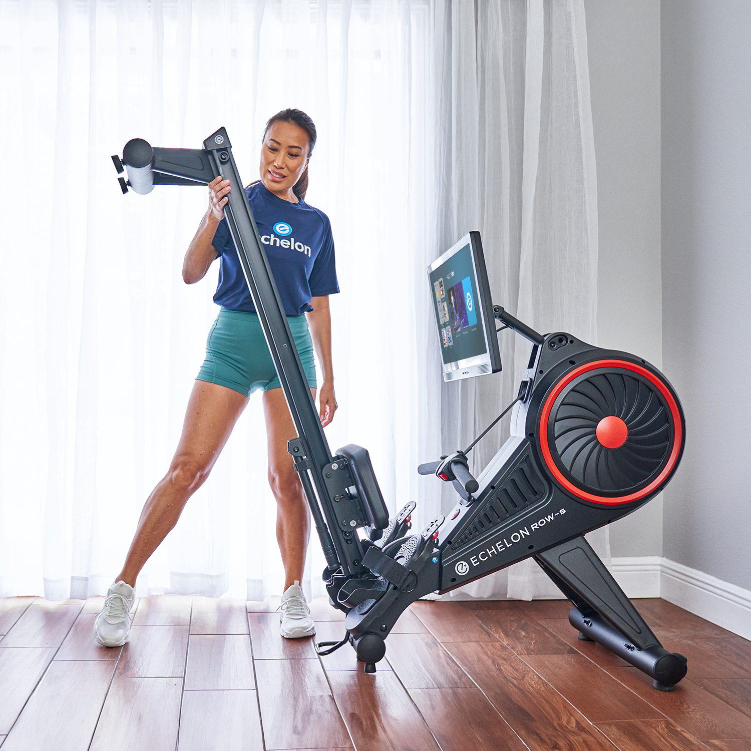 Person adjusting a foldable rowing machine in a bright room.