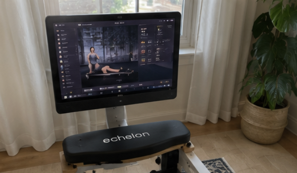 An Echelon rowing machine with a screen displaying a fitness class in a room with a large window.
