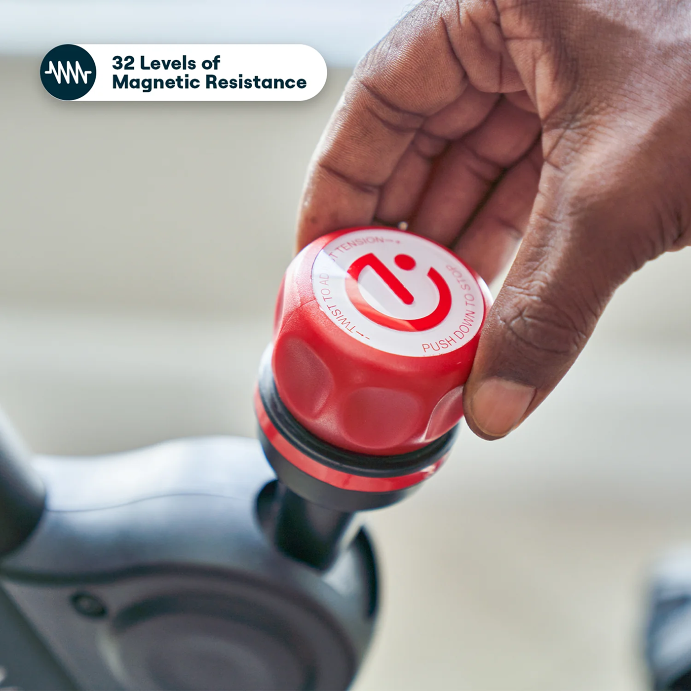Hand adjusting a red resistance knob on exercise equipment.