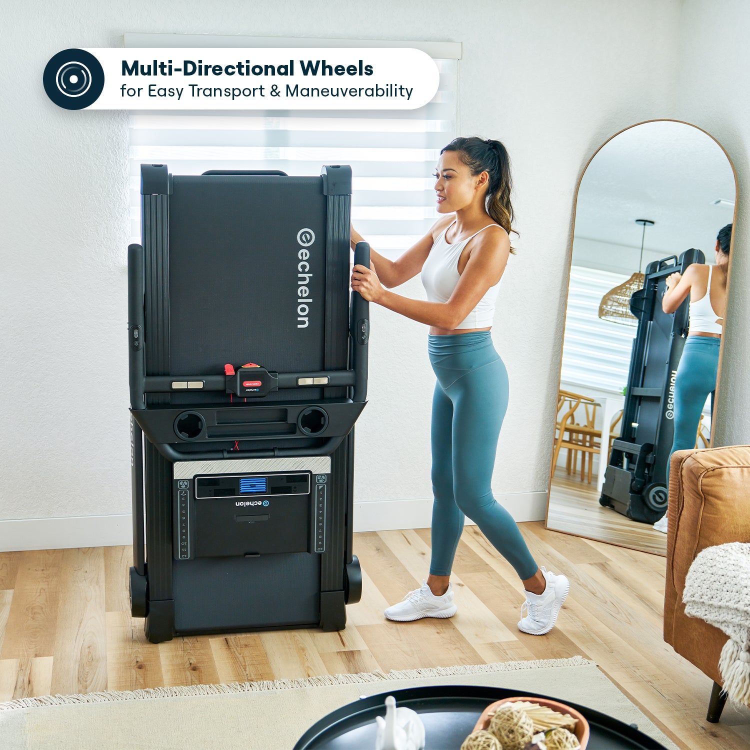 Woman moving a foldable treadmill with multi-directional wheels in a living room.