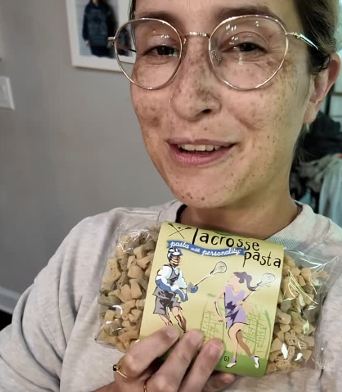 Customer holding a package of Across the Pasta shaped pasta indoors