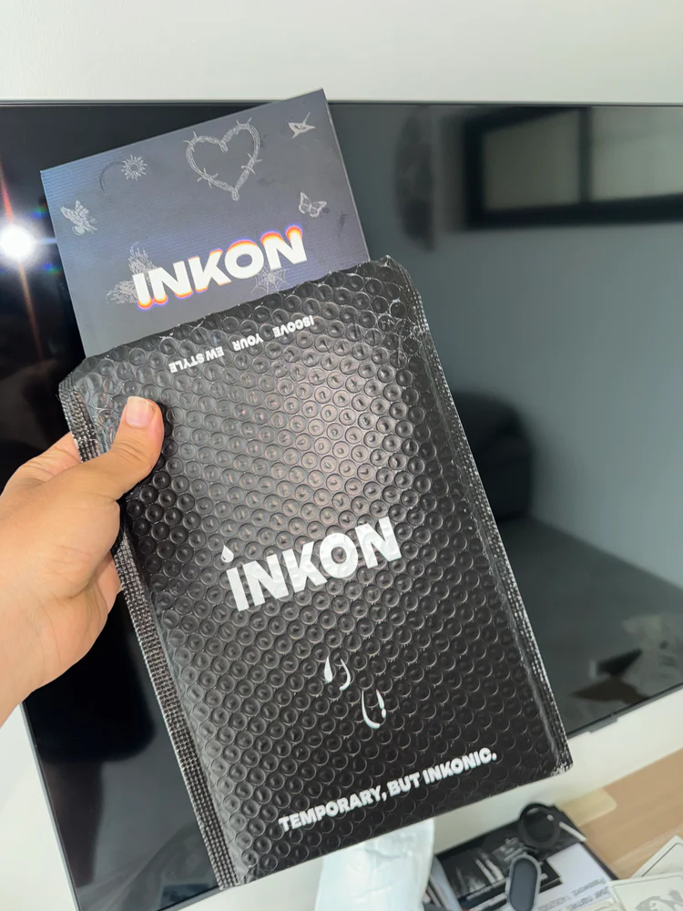 Hand holding a black bubble mailer with 'INKON' branding.