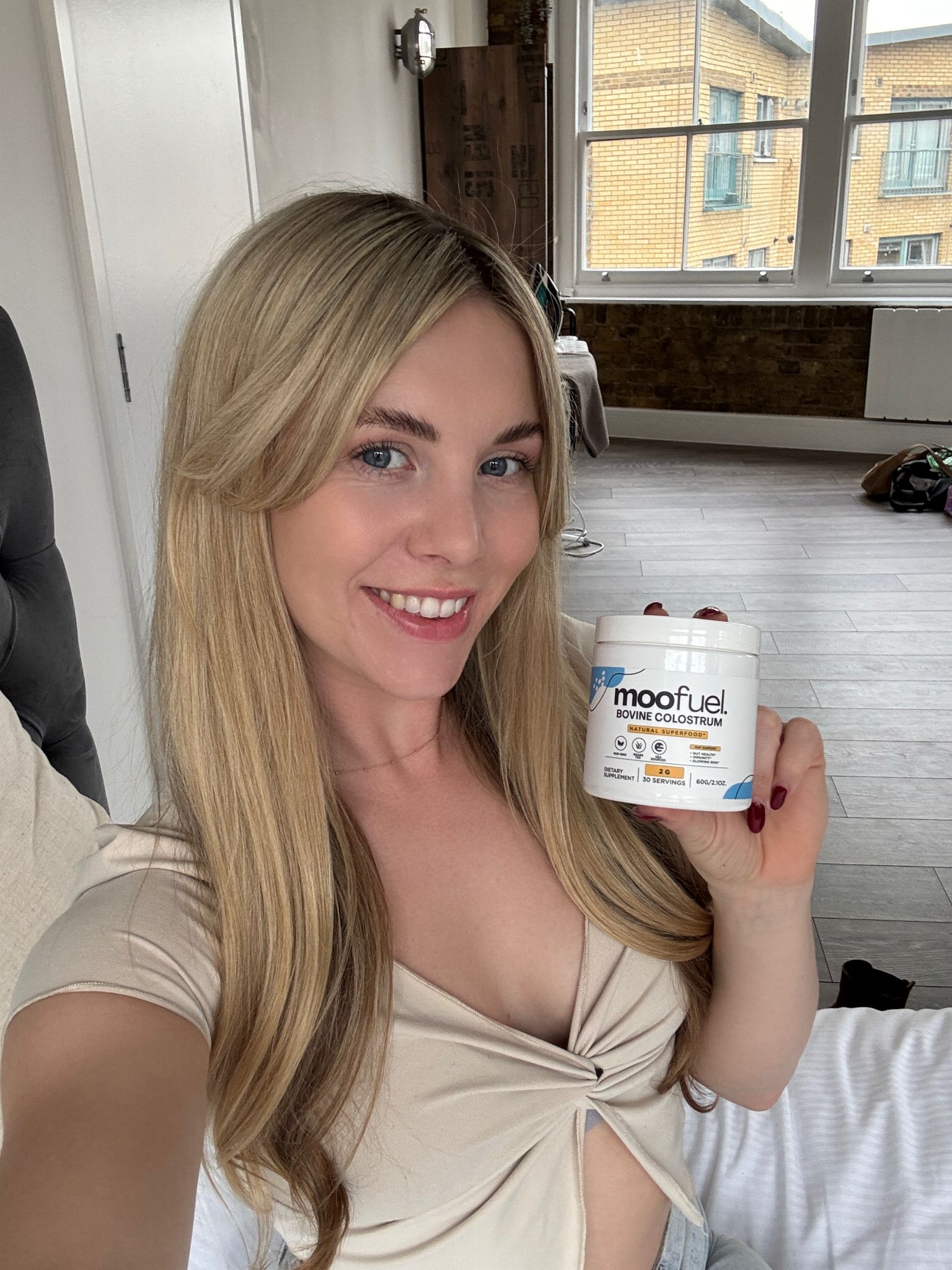 Person holding a container labeled 'moofuel' in a room with large windows.