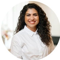 Person smiling in a white shirt with curly hair.