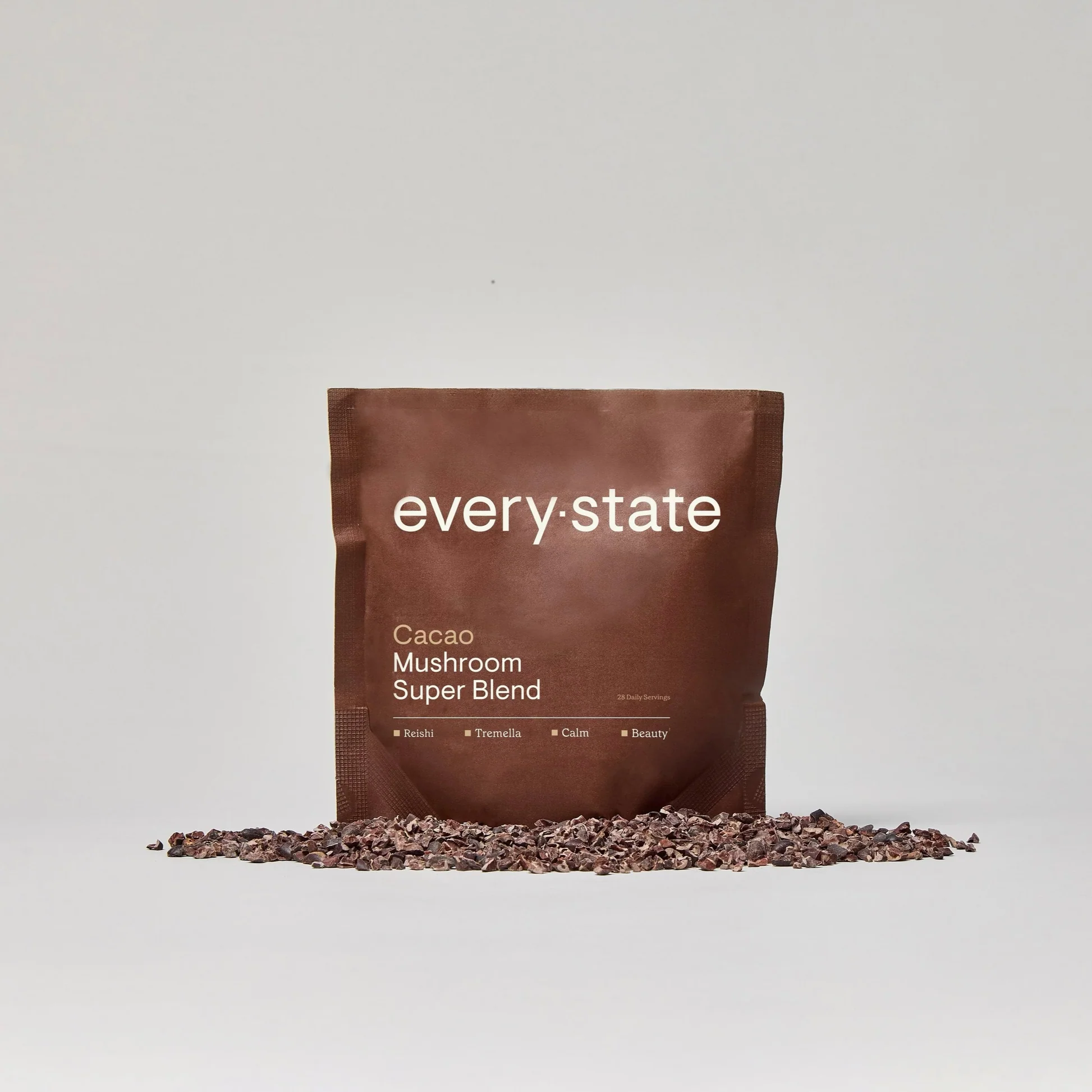 Brown pouch labeled 'every:state Cacao Mushroom Super Blend' with cacao nibs scattered in front.