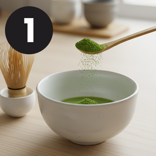 Matcha powder being sprinkled from a wooden spoon into a white bowl next to a bamboo whisk.