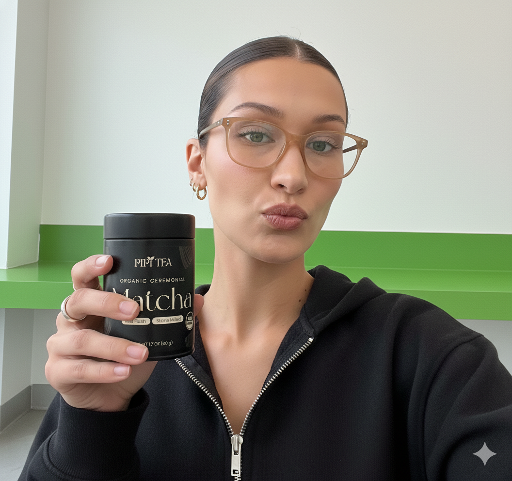 A woman in glasses and a black hoodie holds up a black canister of matcha tea.