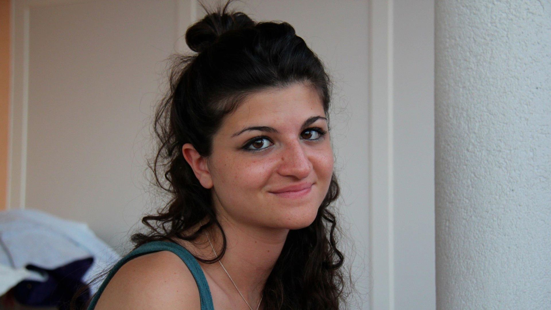 A young woman with dark hair tied in a bun, smiling slightly at the camera.