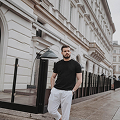 Person in black shirt and white pants walks by a historic building.
