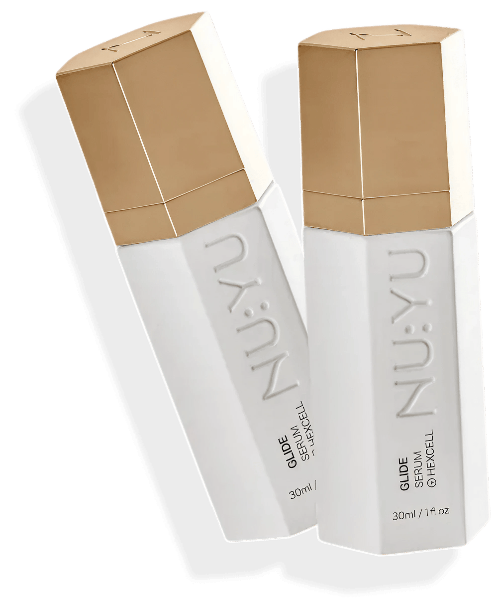 Two hexagonal bottles with gold caps labeled 'NU:YU Glide Serum'.