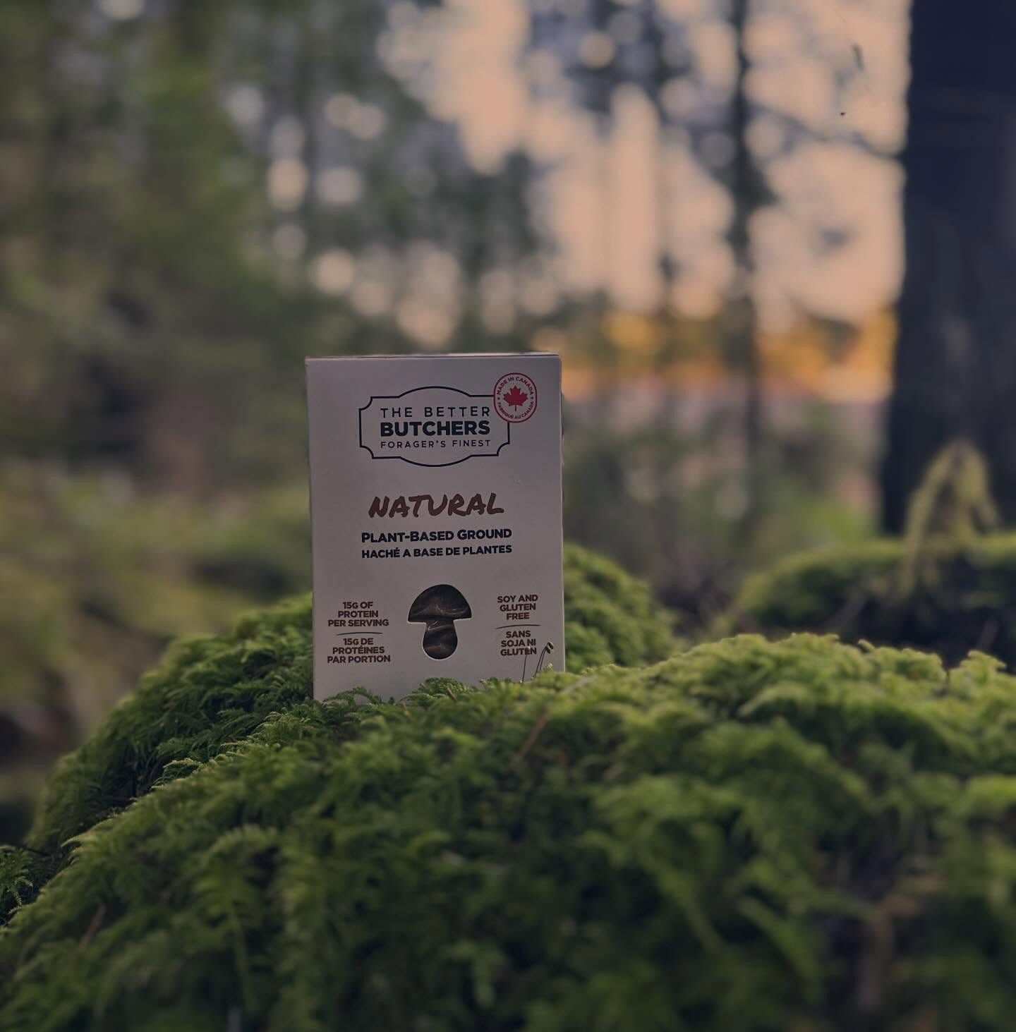 A box of The Better Butchers plant-based ground sits on a bed of green moss in a forest.