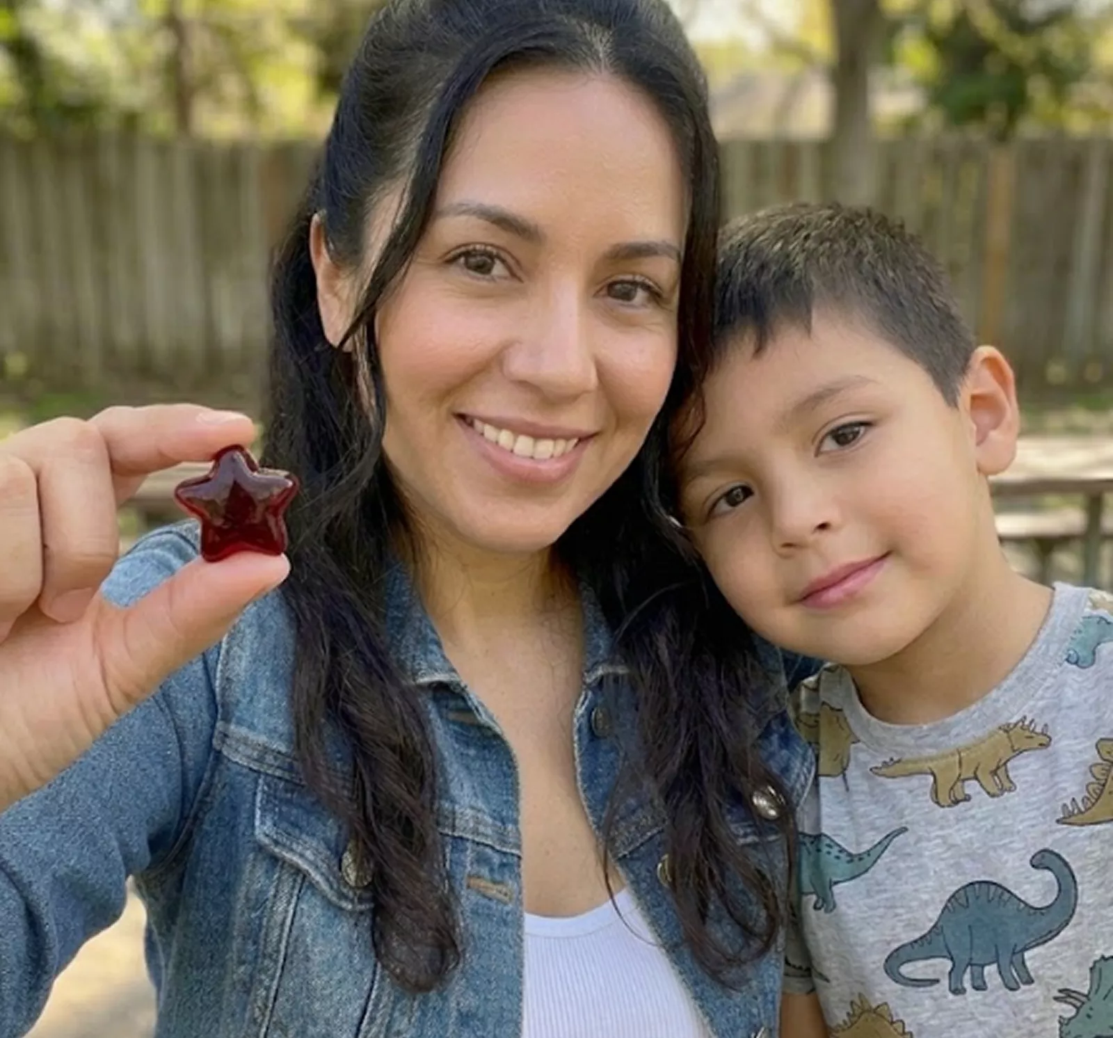 A woman and a young boy smile, while the woman holds up a red, star-shaped gummy candy.