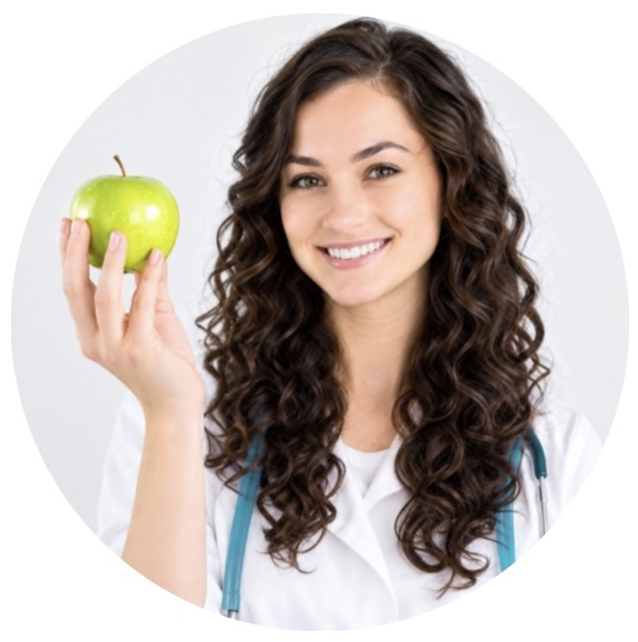 A smiling female doctor with a stethoscope holds up a green apple.