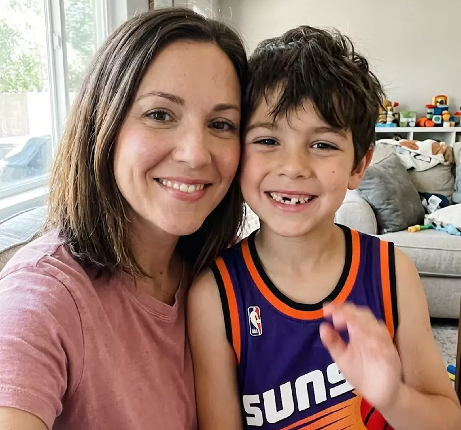 A woman and a young boy in a Phoenix Suns basketball jersey smiling for the camera.