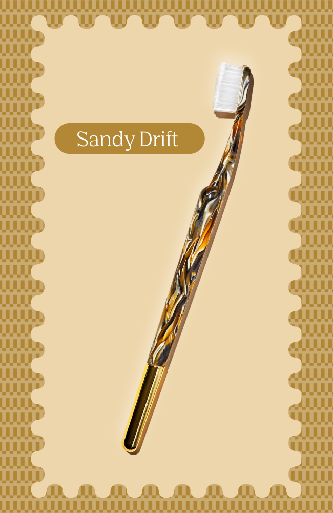 Decorative toothbrush with wavy brown handle, labeled 'Sandy Drift'.