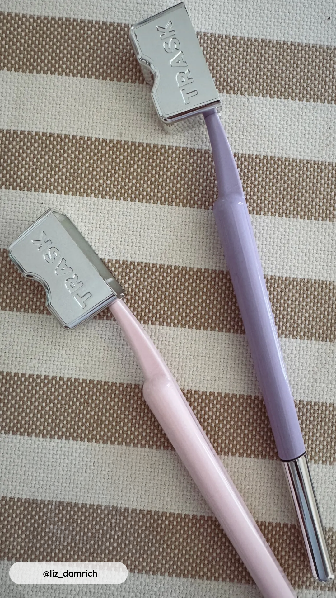 Two razors with metallic heads on a striped fabric background.