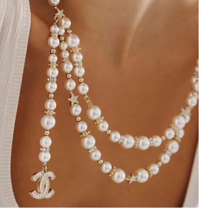 A pearl necklace with a logo pendant and star accents.