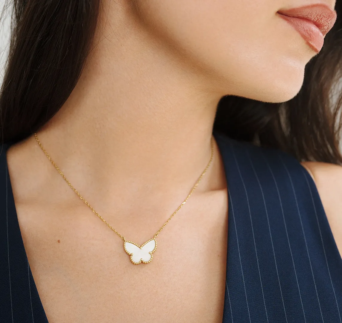 Woman wearing a butterfly necklace on a gold chain.