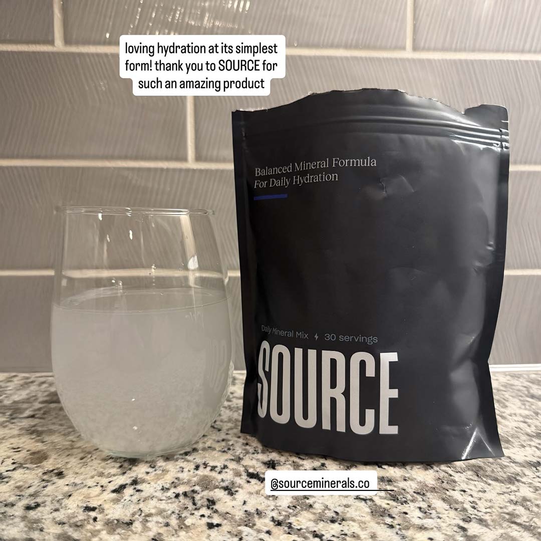 Glass of water and a black SOURCE mineral mix package on a countertop.