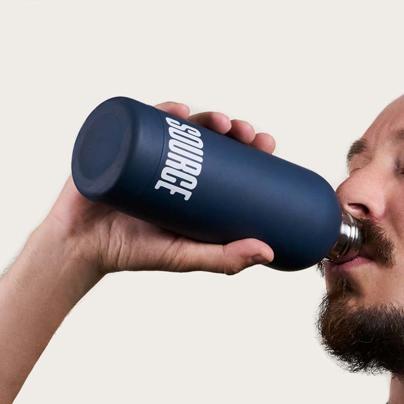 Person drinking from a blue reusable bottle with 'SOURCE' written on it.