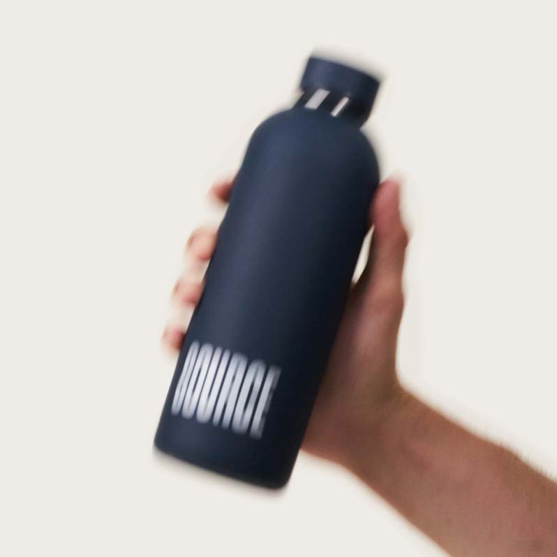 A hand holding a black water bottle with 'SOURCE' written on it.
