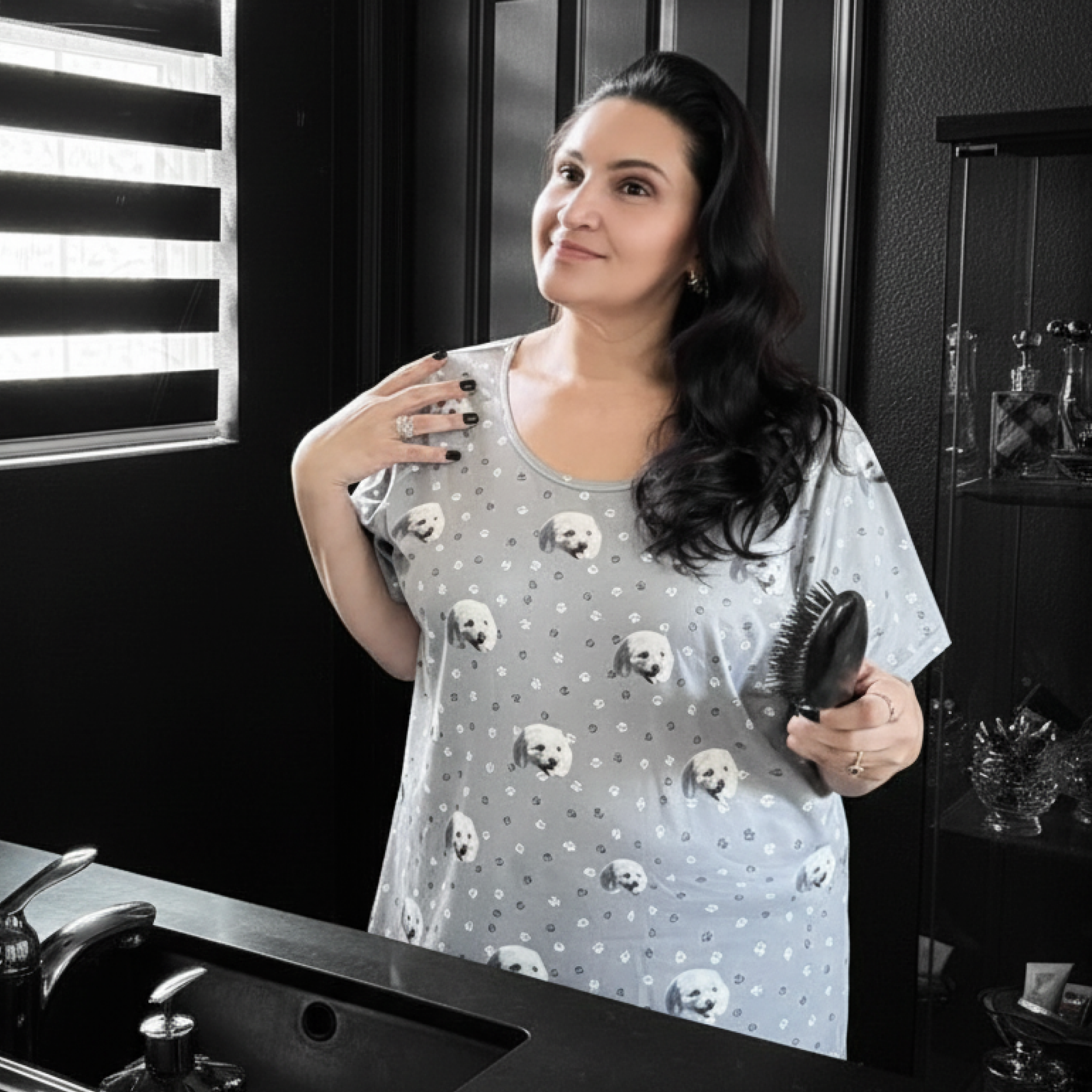 Woman in paw-print dog-face nightgown brushes hair in a bright bathroom.