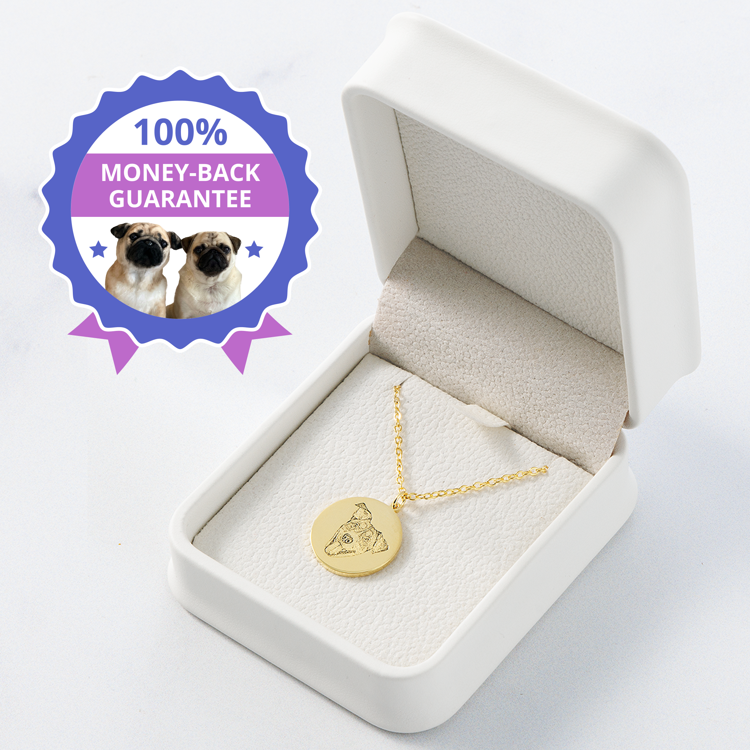 A close-up of an open, white velvet-lined jewelry box containing a gold circular pendant necklace. The pendant is engraved with the portrait outline of a dog's head.
