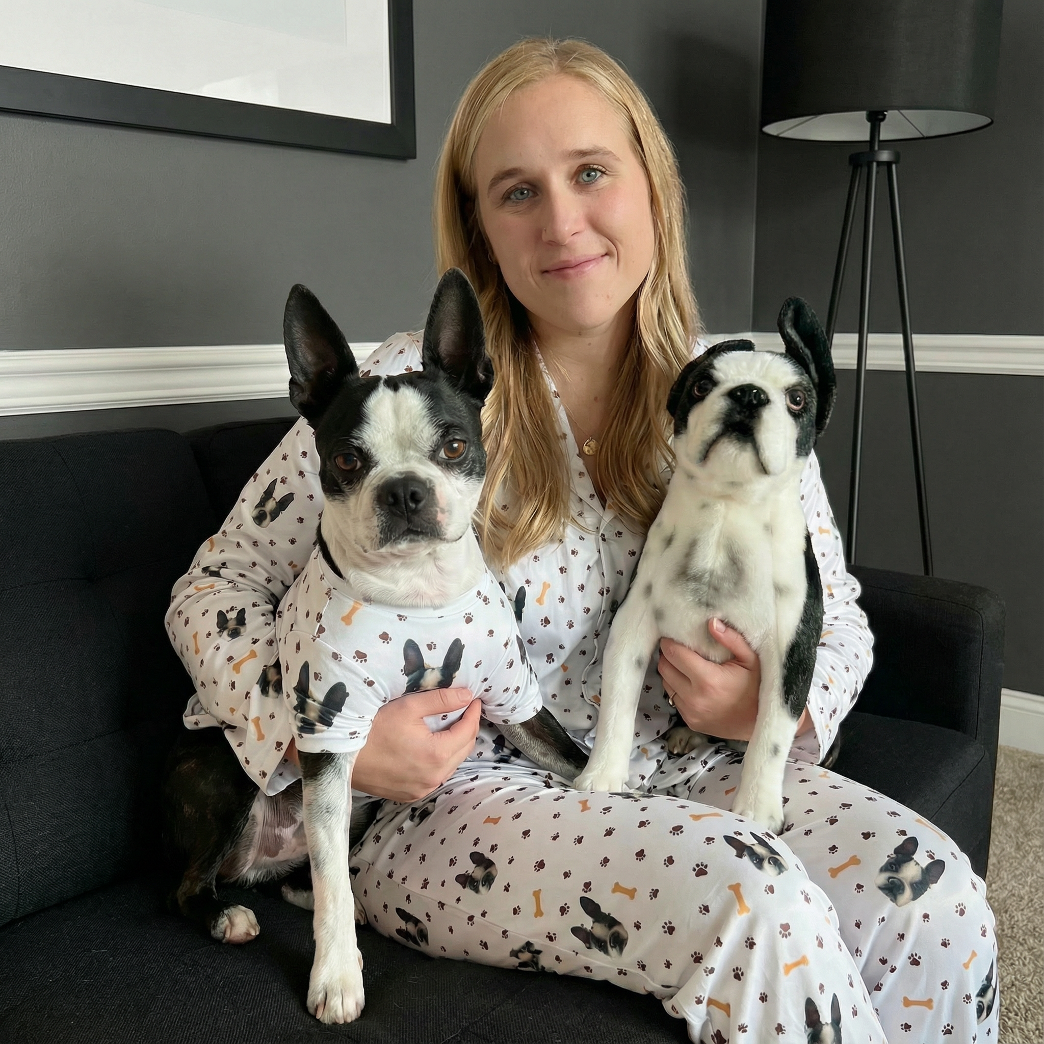 A woman sitting on a couch with a Boston Terrier and a plush toy of the dog.
