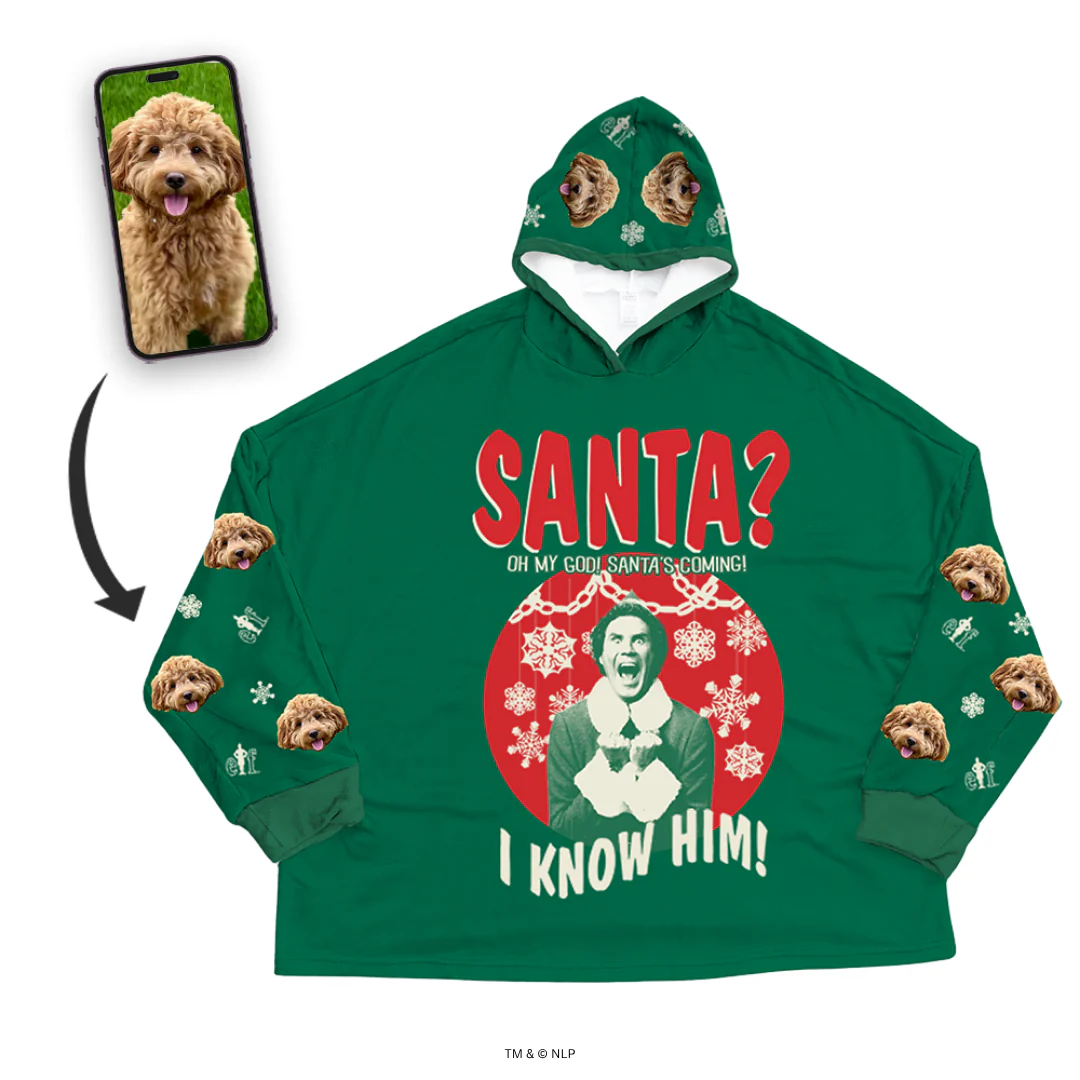 A green oversized hooded blanket/sweatshirt featuring a graphic of Buddy the Elf with the text 'SANTA? OH MY GOD! SANTA'S COMING! I KNOW HIM!' 