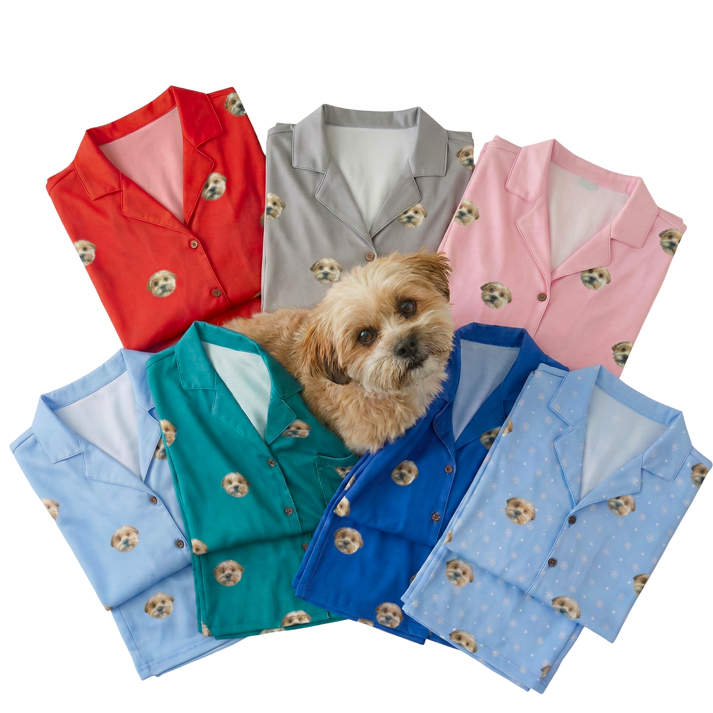 A small, fluffy brown and white dog with expressive eyes is positioned in the center of a fan arrangement of six colorful pajama tops. The pajamas—in shades of red, gray, pink, light blue, emerald green, and royal blue.