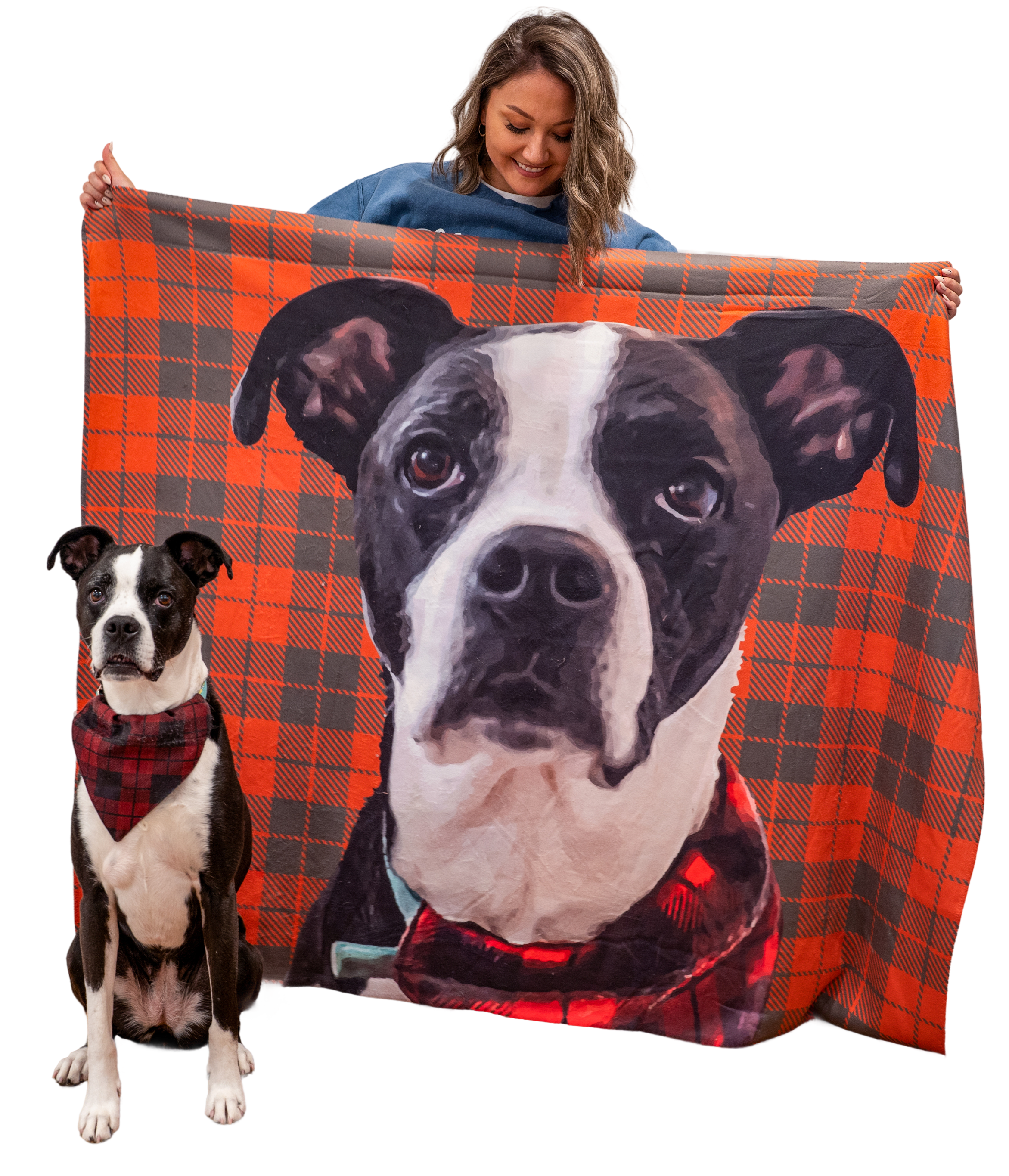 A woman holds up an orange and gray plaid blanket featuring a large portrait of a black and white dog. The real dog, wearing a matching red plaid bandana, sits beside her.