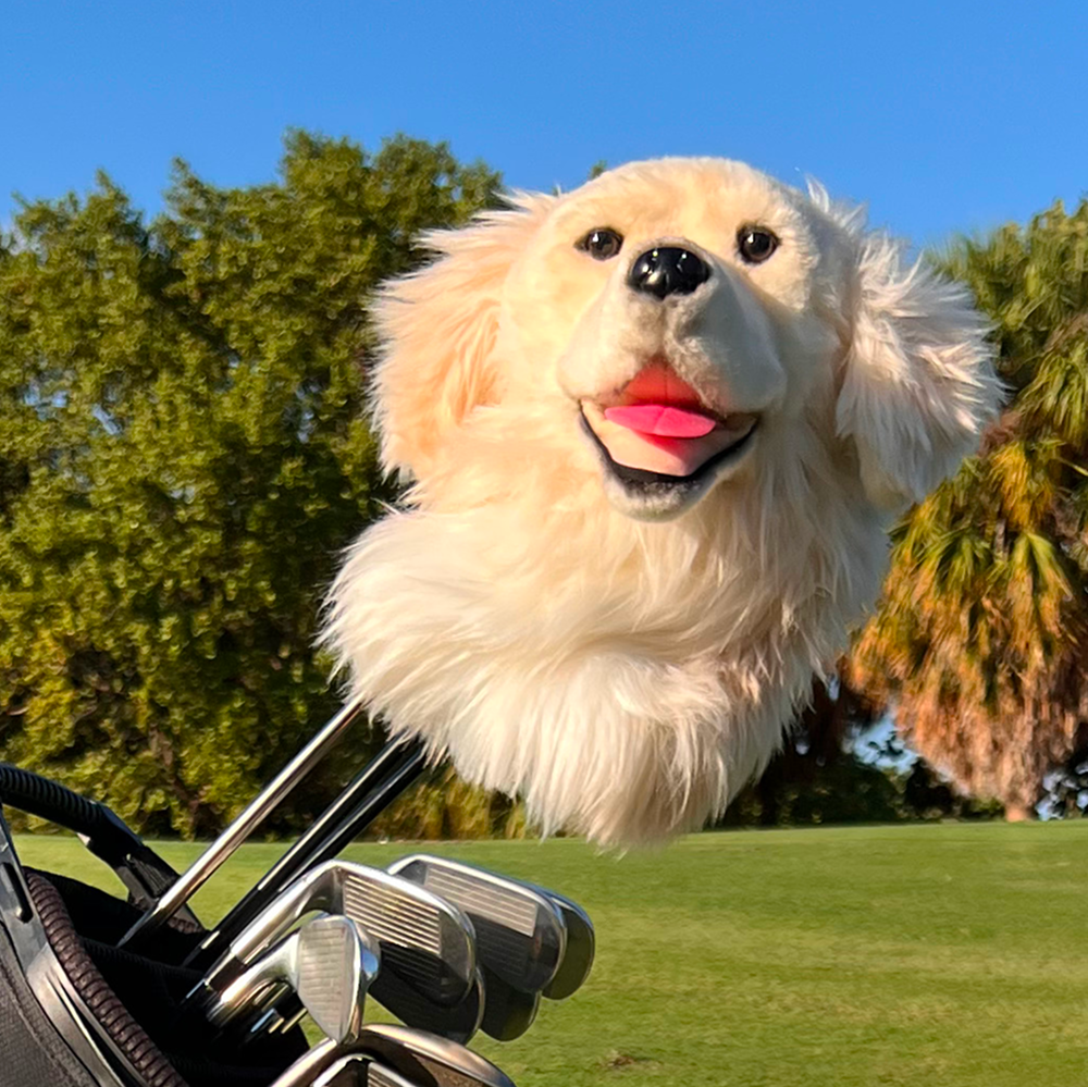 Golf club head cover shaped like a dog's head on a golf course.