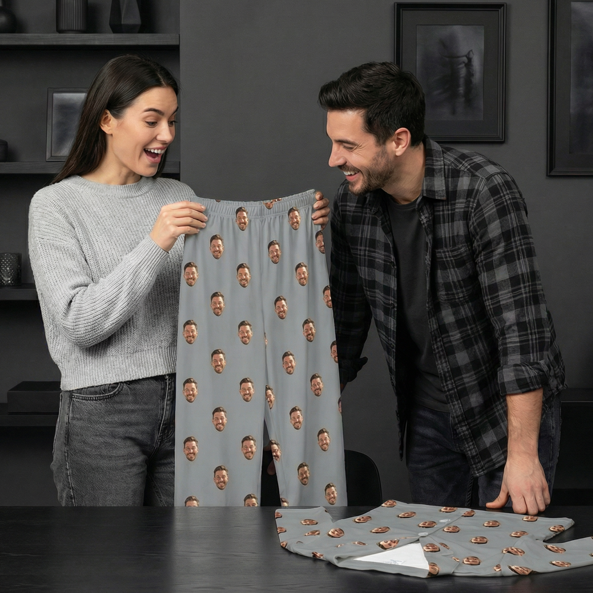 Couple laughing while holding custom face-print pajama pants in a modern dark-toned room.