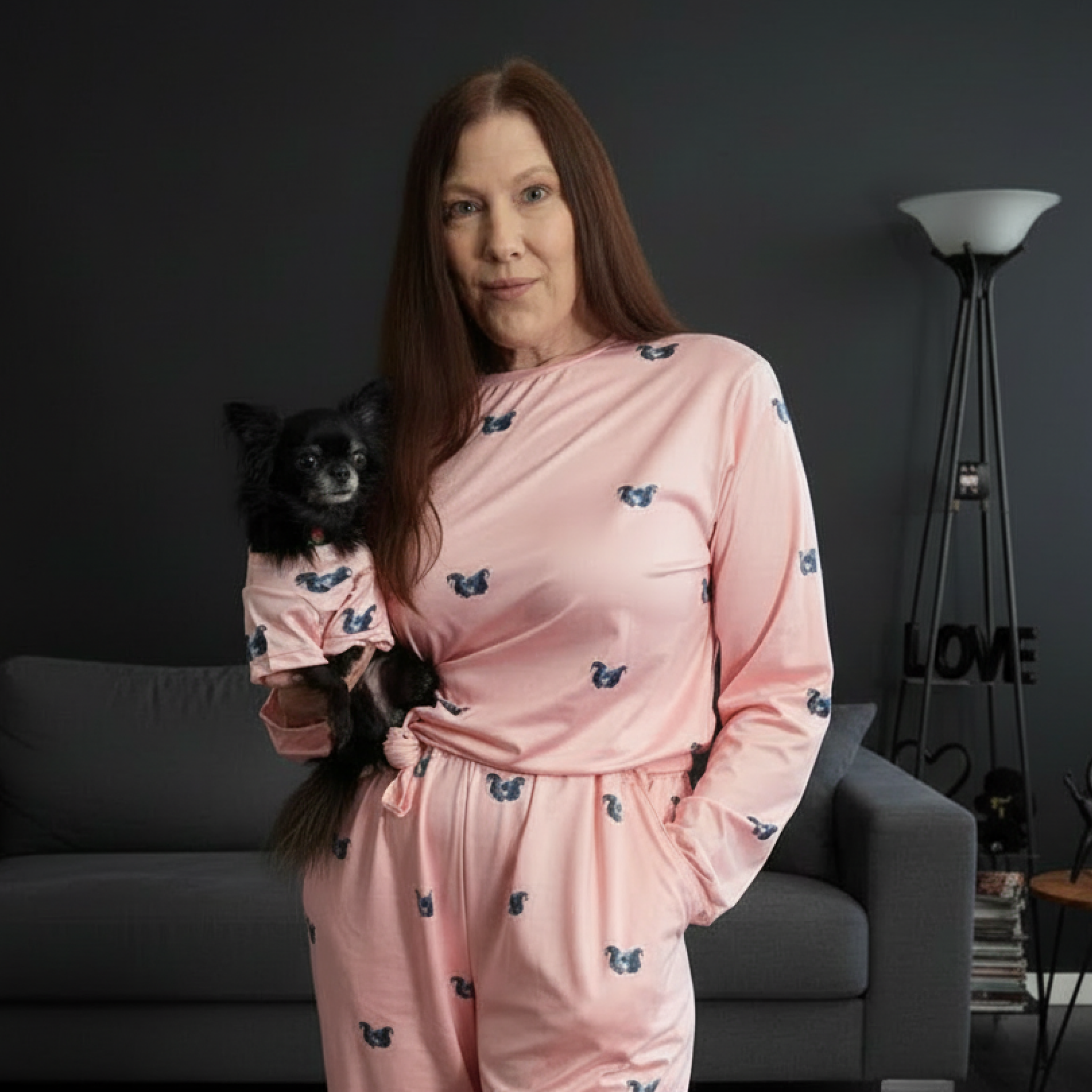 Woman and small dog in matching pink pajamas with blue dog-print patterns.