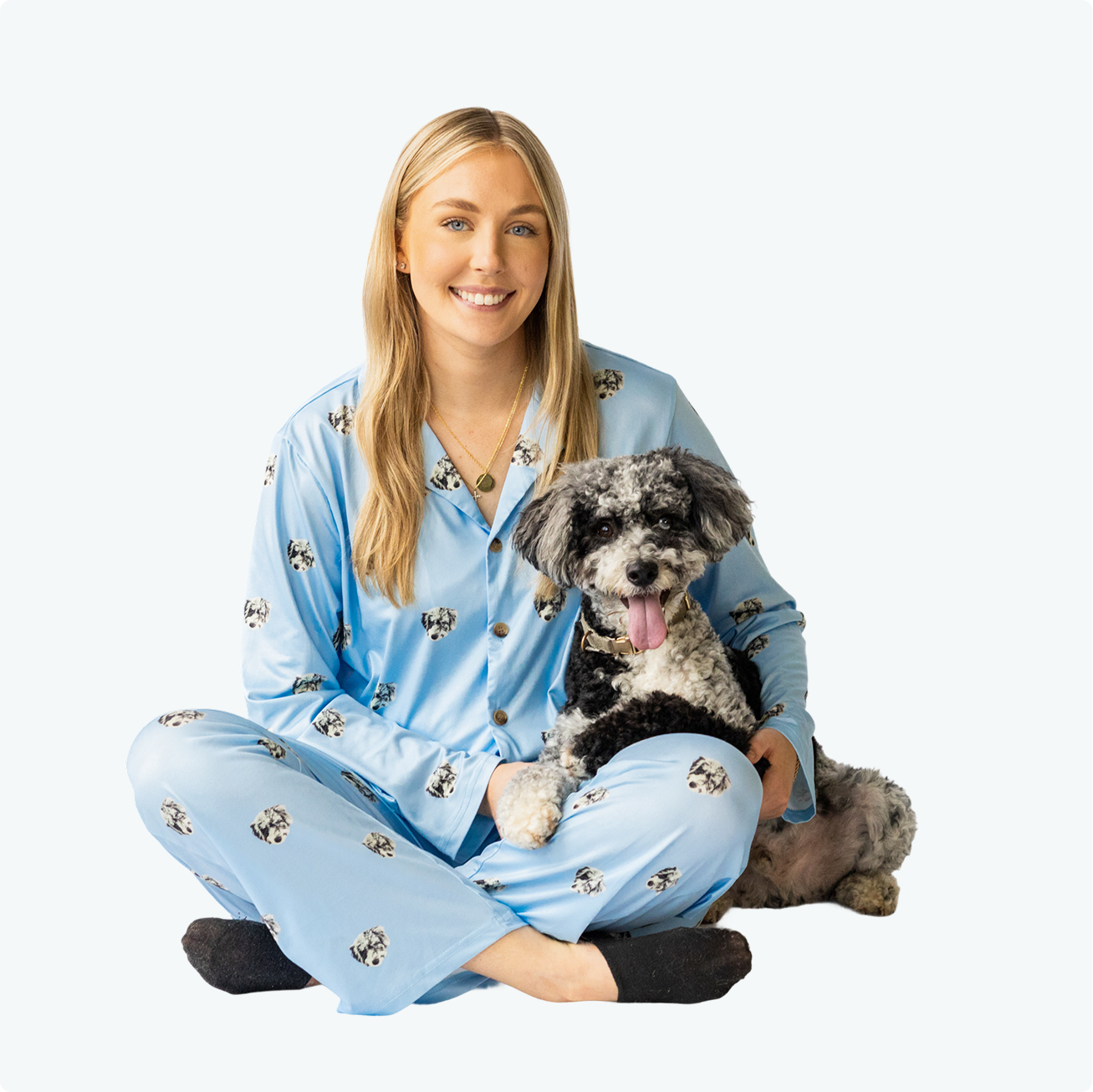 Person in blue pajamas sitting with a black and white dog.