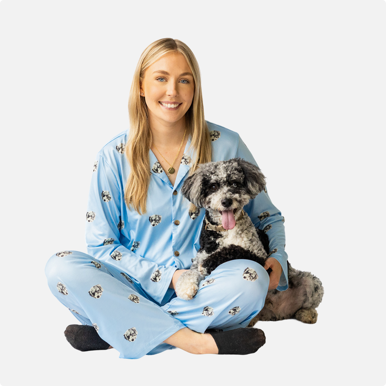 Person in blue pajamas sitting with a black and white dog.