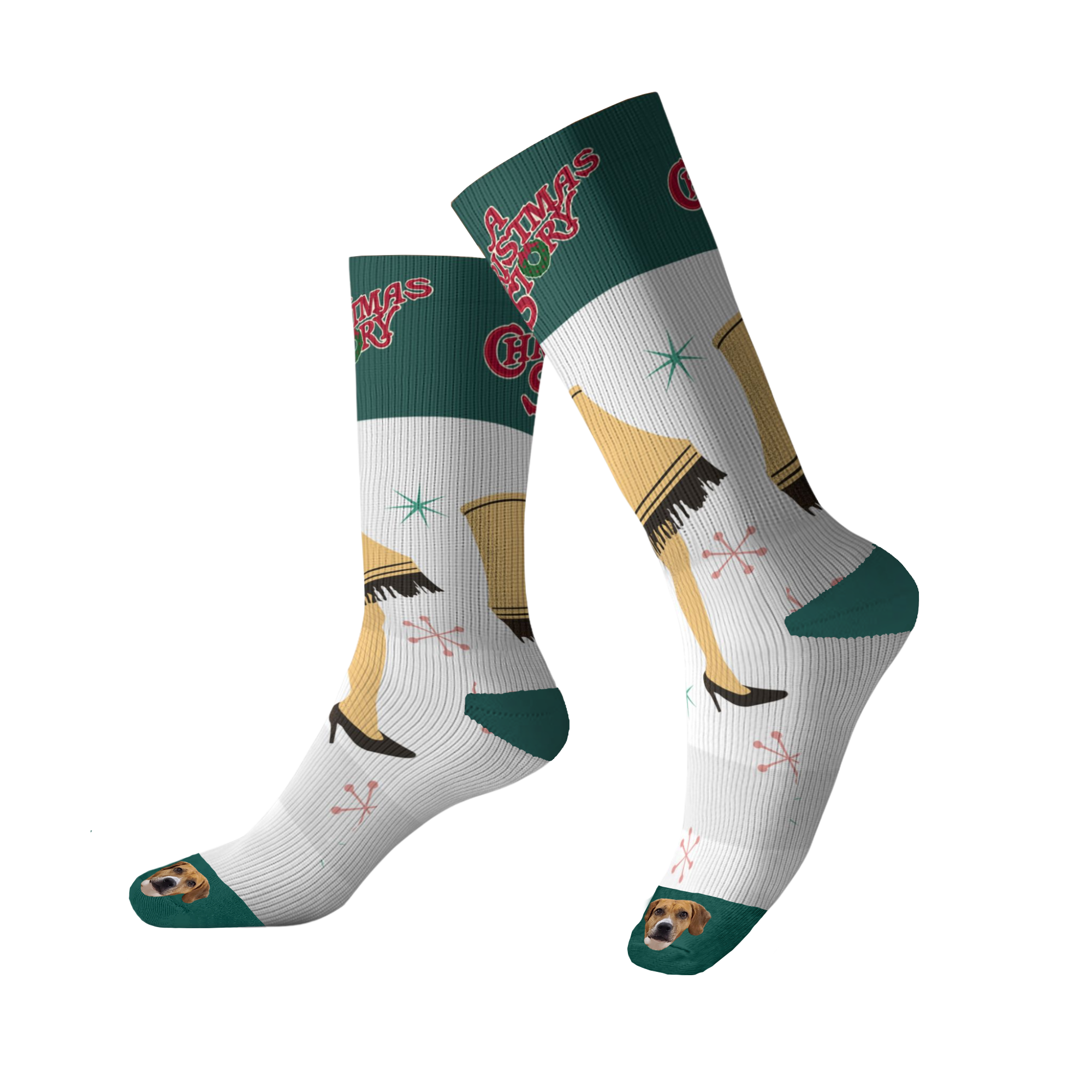 A pair of tall white socks with green cuffs and soles, featuring graphics of the Leg Lamp from A Christmas Story and the movie title, interspersed with pink and green starbursts. The toe of each sock features an image of a brown and white dog's face. The socks are shown on a black backgroun