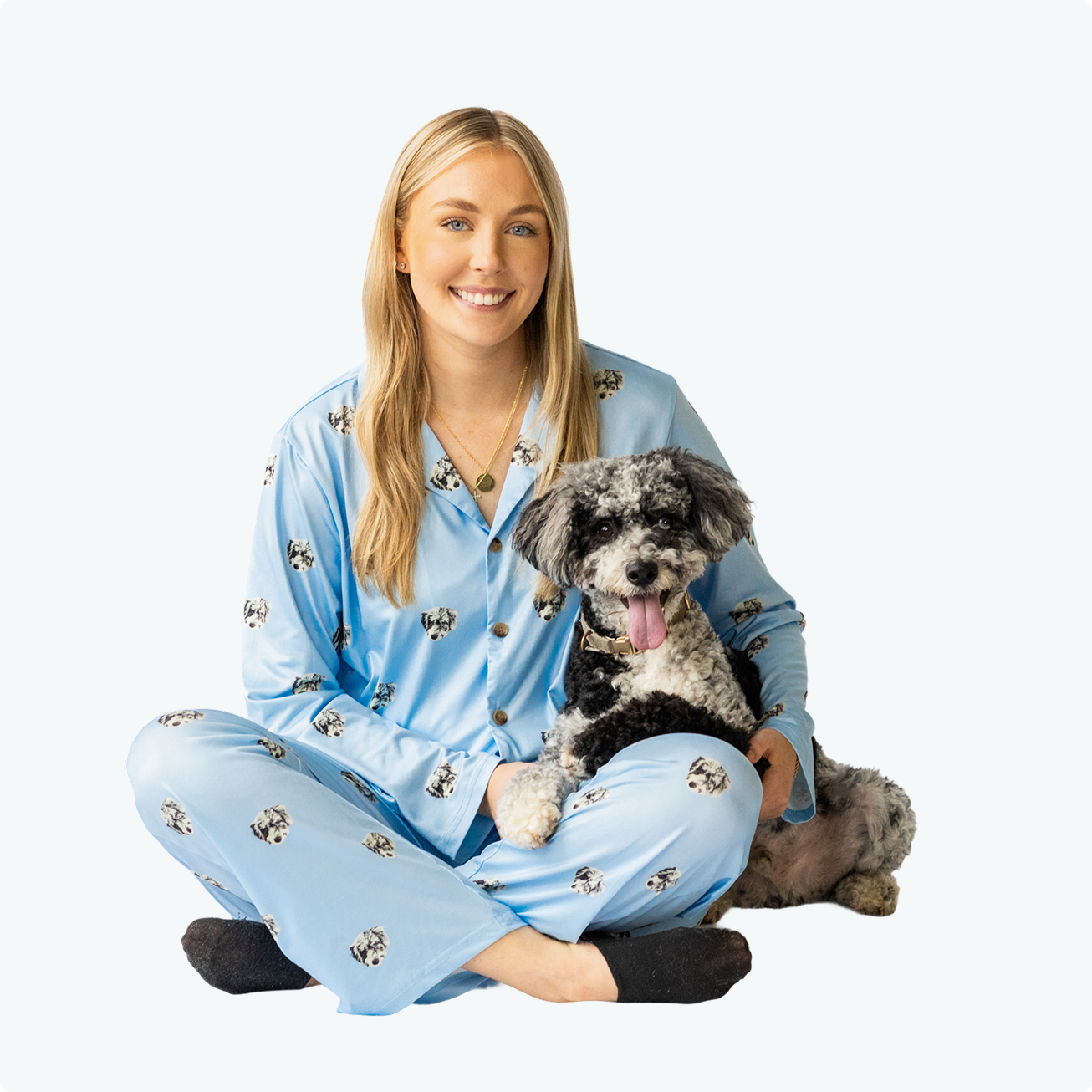 Person in blue pajamas sitting with a small dog.