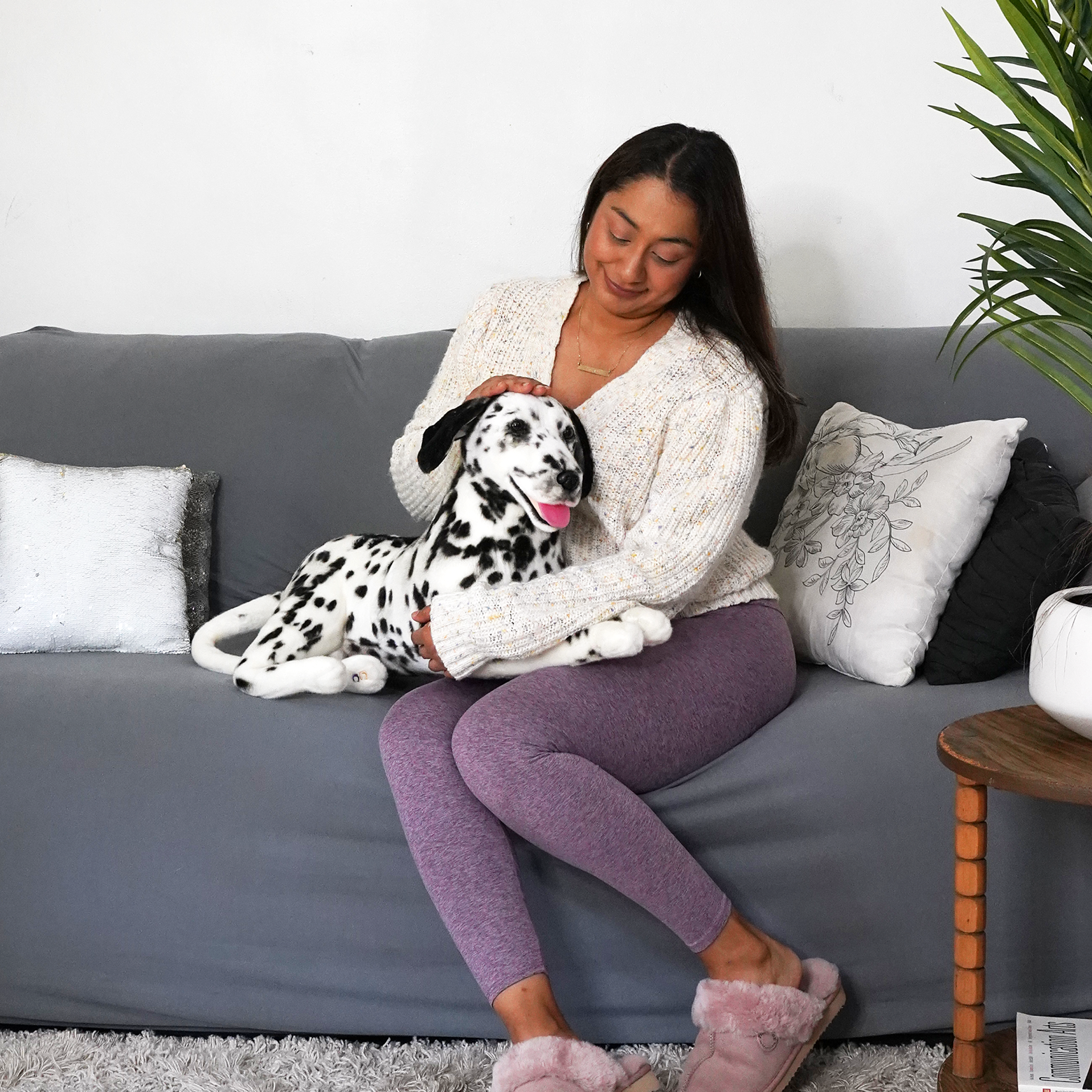 Woman on sofa with a stuffed Dalmatian toy on her lap.