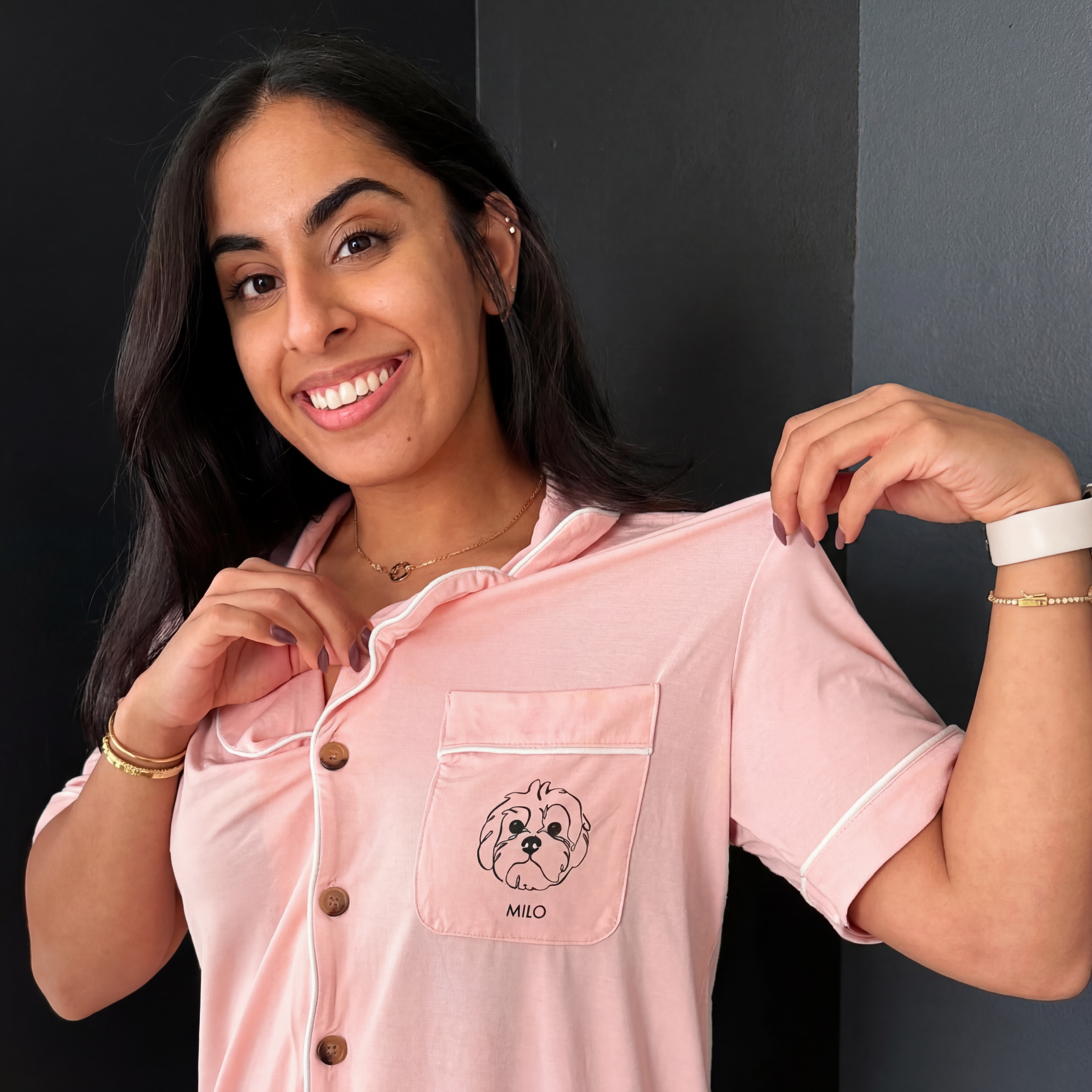 Woman wears pink PJ top with dog line art on pocket.